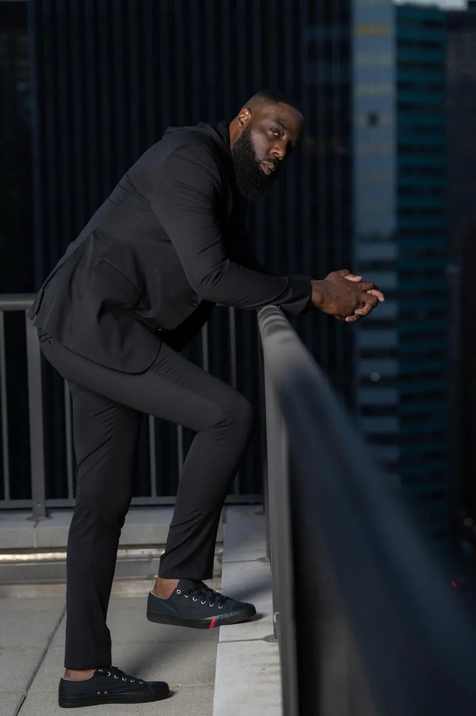 Neil Anthony Edwards in a black suit on a city rooftop.